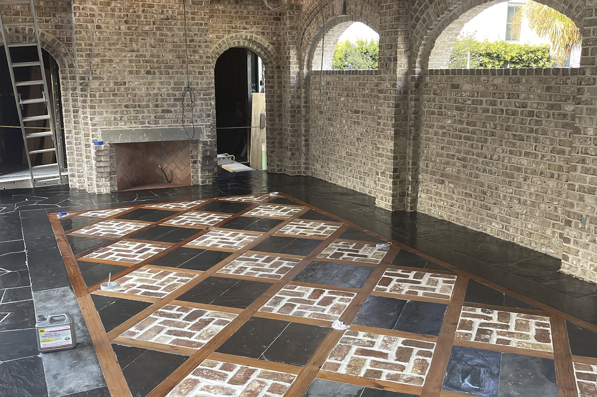 Brick room with arched windows, a fireplace, and a floor featuring a diamond pattern of black tiles and bricks.